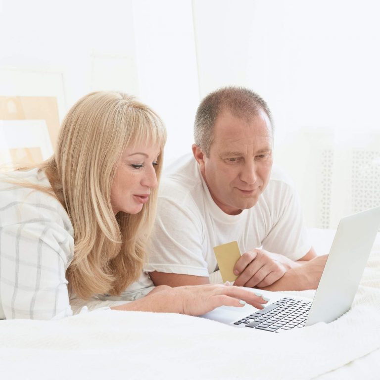 Mature family couple looking at laptop screen. Happy middle aged man holding credit card